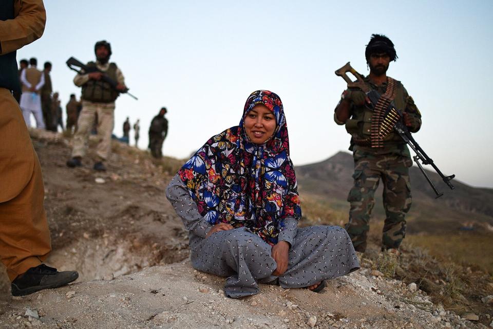 This photograph taken on July 14, 2021 shows Salima Mazari (C), a female district governor in male-dominated Afghanistan, looking on from a hill while accompanied by security personnel near the frontlines against the Taliban at Charkint district in Balkh province. - Mazari, a female district governor in male-dominated Afghanistan, is on a mission -- recruiting menfolk to fight the Taliban.