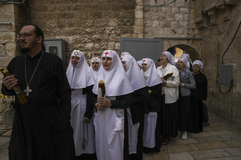 Orthodox Christians clergy and nuns hold candles as they arrive for the Holy Fire ceremony, a day before Easter, at the Church of the Holy Sepulcher, where many Christians believe Jesus was crucified, buried and resurrected, in Jerusalem's Old City, Saturday, April 15, 2023. (AP Photo/Mahmoud Illean)