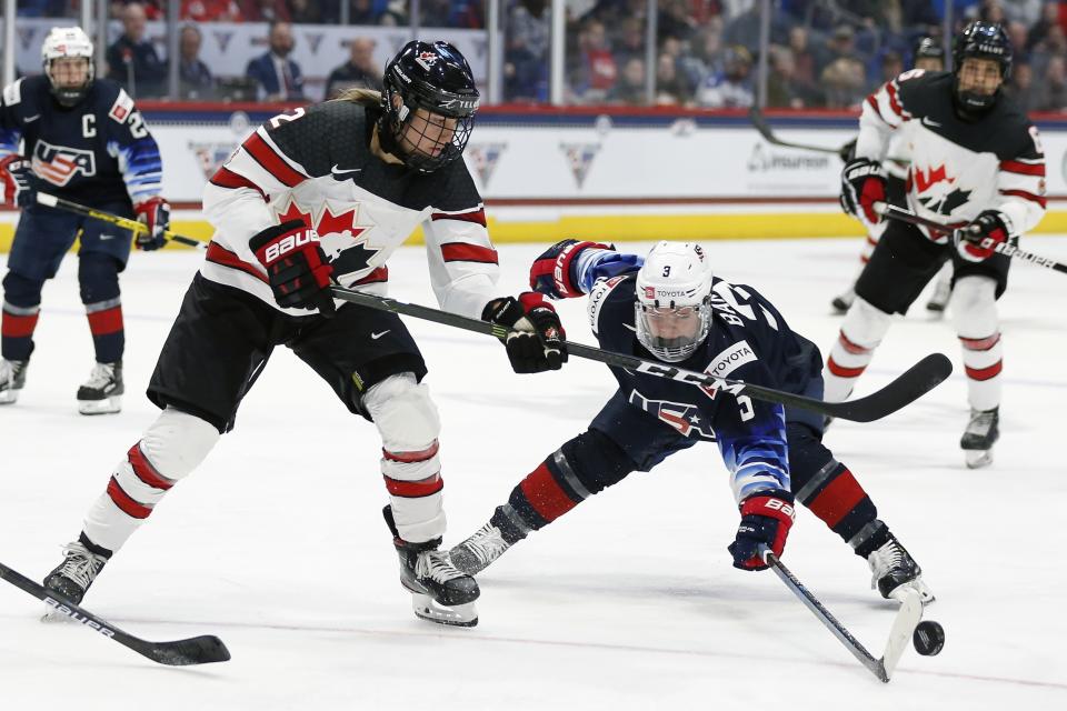 Canada's Meghan Agosta (2) and United States' Cayla Barnes (3) battle for the puck during the second period of a rivalry series women's hockey game in Hartford, Conn., Saturday, Dec. 14, 2019. (AP Photo/Michael Dwyer)