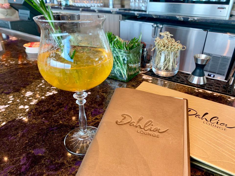 yellow-colored cocktail next to a gold menu at dehlia's at disney world