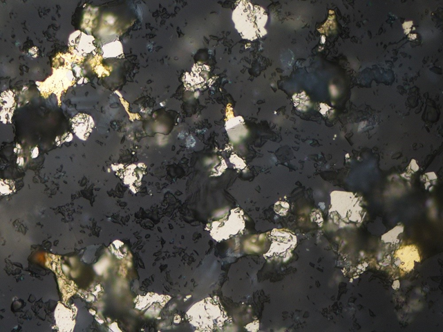 <strong>Photo 3: </strong><i><strong>Sample 2084 (WPT 58): </strong></i><strong>Pyrite, chalcopyrite, and electrum within quartz in the pyrite-rich material. Field of view = 0.6 mm, reflected light.</strong>