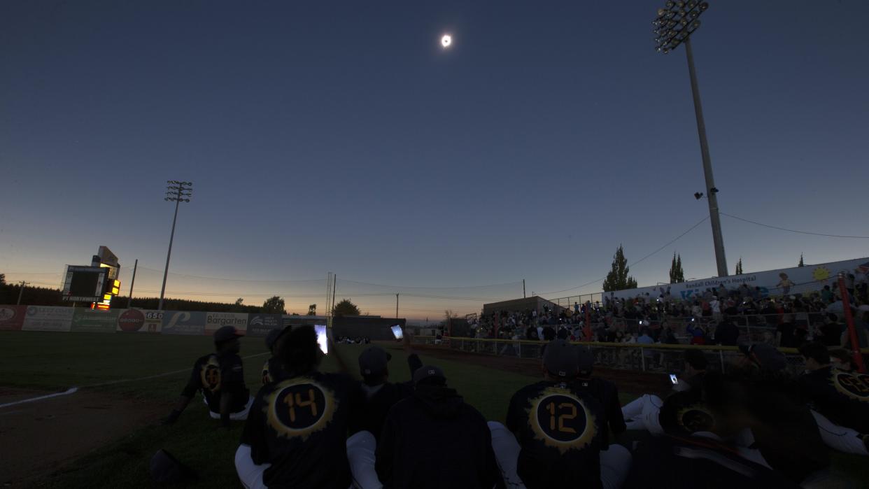  Crowds and players gather below to watch the moon eclipse the sun overhead. . 