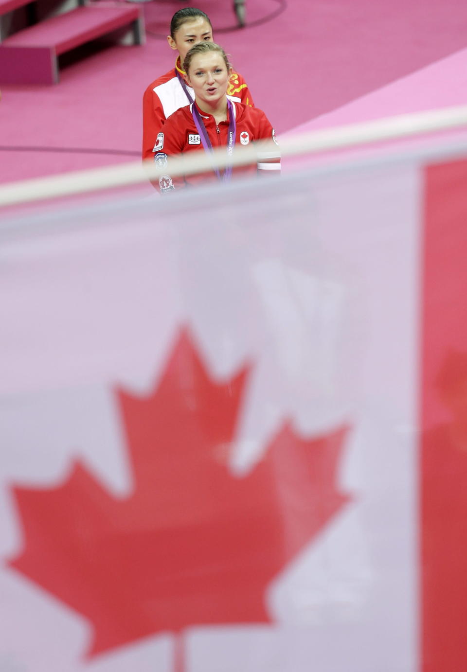 Canada's gold medallist Rosannagh Maclennan walks followed by China's bronze medallist He Wenna after the medal ceremony for the women's trampoline at the 2012 Summer Olympics, Saturday, Aug. 4, 2012, in London. (AP Photo/Julie Jacobson)