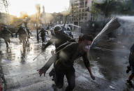 A demonstrator runs away from police during clashes at a protest against police in reaction to a video that appears to show an officer pushing a youth off a bridge the previous day at a protest, in Santiago, Chile, Saturday, Oct. 3, 2020. (AP Photo/Esteban Felix)