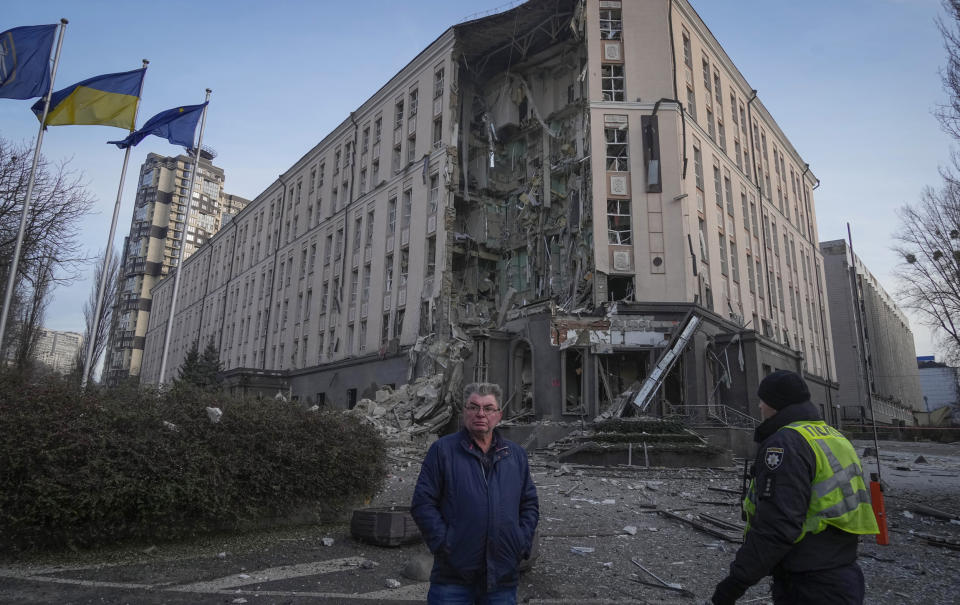 People stand in front of damaged hotel at the scene of Russian shelling in Kyiv (Efrem Lukatsky / AP)