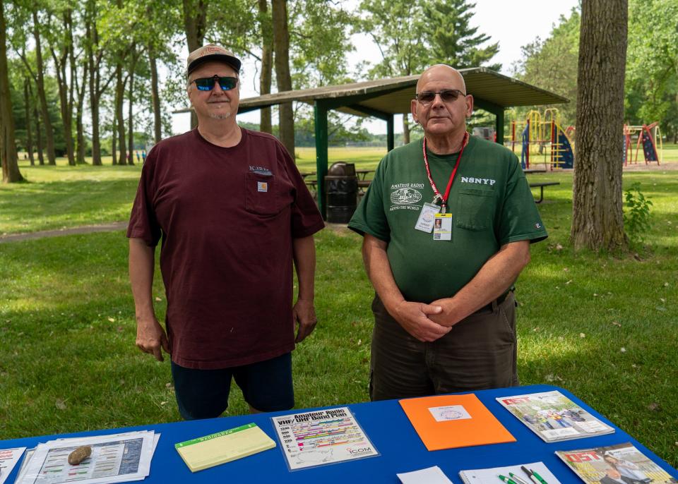 Keith Hutchinson, left, and Terry Kolton stand by an information table at the annual American Radio Relay League Field Day on June 25.