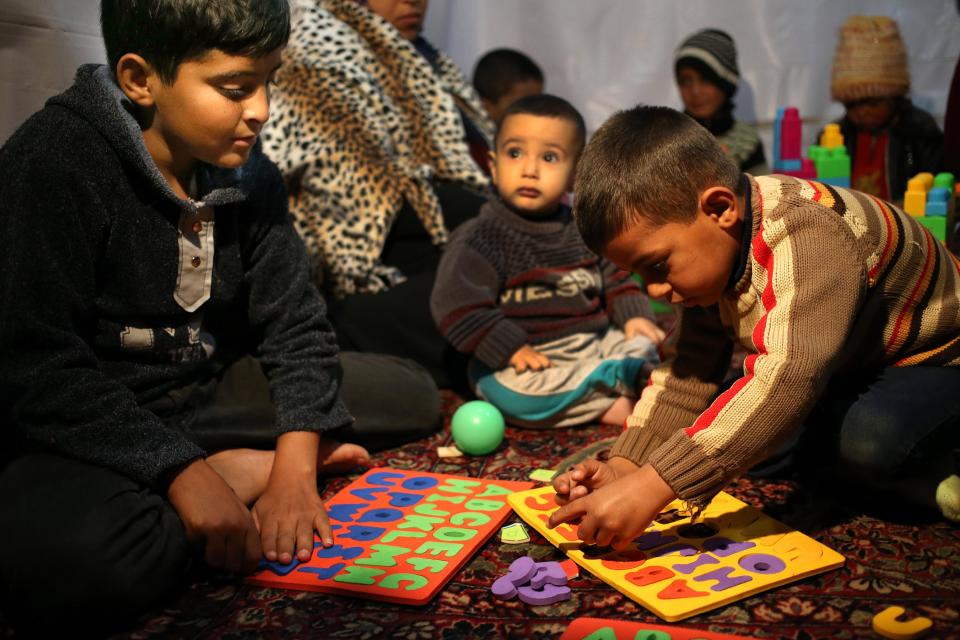 In this picture taken on Wednesday, March 12, 2014, Syrian refugee boys Anas, 13, left, and Saleh el-Hussein, 5, right, follow a lesson about the English alphabets inside a tent, a home for a refugee family that turns into a makeshift school in a refugee encampment in the Lebanese-Syrian border town of Majdal Anjar, eastern Bekaa valley, Lebanon. More than 2 million of those who should be in school remain in Syria, where classrooms have been bombed, used as shelters or turned into military barracks. Another 300,000 Syrian children don’t attend school in Lebanon, along with some 93,000 in Jordan, 78,000 in Turkey, 26,000 in Iraq and 4,000 in Egypt, UNICEF officials in Geneva said. Those numbers likely are higher, as UNICEF can’t count the children whose parents didn’t register with the United Nations refugee agency. (AP Photo/Hussein Malla)