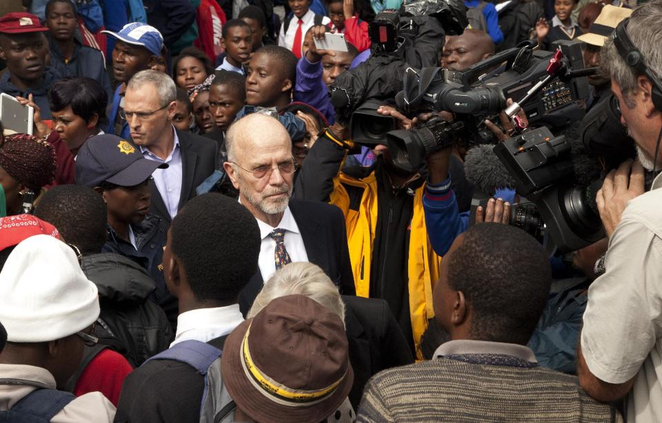 Oscar Pistorius's uncle Arnold Pistorius, center, surrounded by media and members of the public as he leaves the high court in Pretoria, South Africa, Tuesday, March 4, 2014. Oscar Pistorius is charged with murder for the shooting death of his girlfriend, Reeva Steenkamp, on Valentines Day in 2013. (AP Photo/Themba Hadebe)