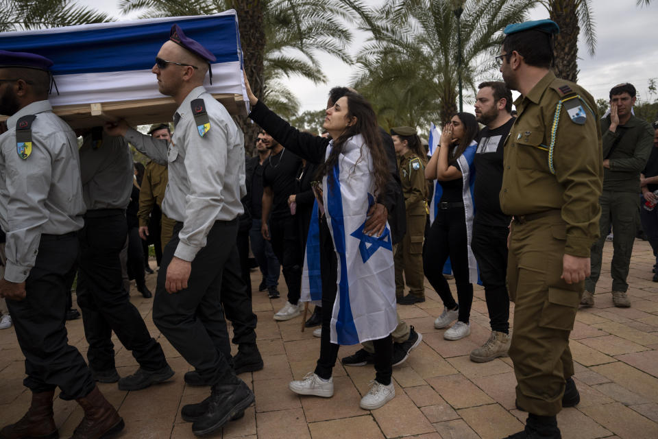 The wife of Israeli reservist Yair Cohen touches his flag-draped casket during his funeral at Kiryat Shaul military cemetery in Tel Aviv, Israel, Tuesday, Feb. 13, 2024. (AP Photo/Oded Balilty)