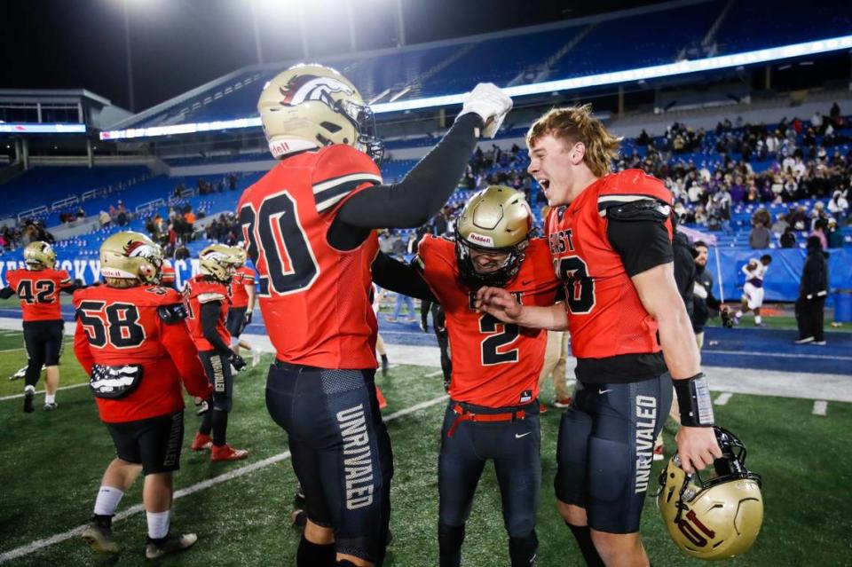 Bullitt East’s Travis Egan (10), Camron Brogan (2) and Nolan Davenport (20) celebrate after helping to execute the game-winning two-point conversion with 53 seconds left to play.