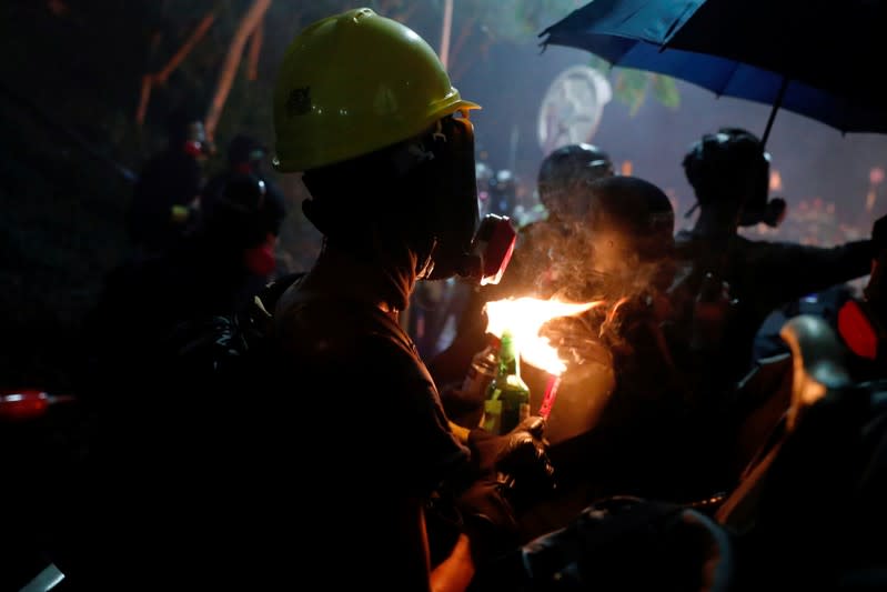 Anti-government protesters take cover during a standoff with riot police at the Chinese University of Hong Kong, Hong Kong