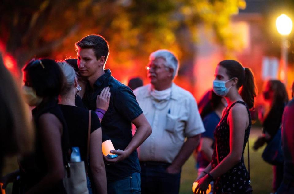 Carson Tibbitts, left, is embraced by people attending a vigil for his aunt, Mary Kate Tibbitts, at Sacramento’s Plaza Cervantes Park in 2021. Casey Tibbitts, seen in front of a glow from several ambulances that encircled the park in honor, spoke during the vigil about watching a 49ers game with his aunt. Authorities said they found Tibbitts, who was killed along with her two dogs, on the morning of Sept. 3 after her 11th Avenue home was set on fire by her killer.