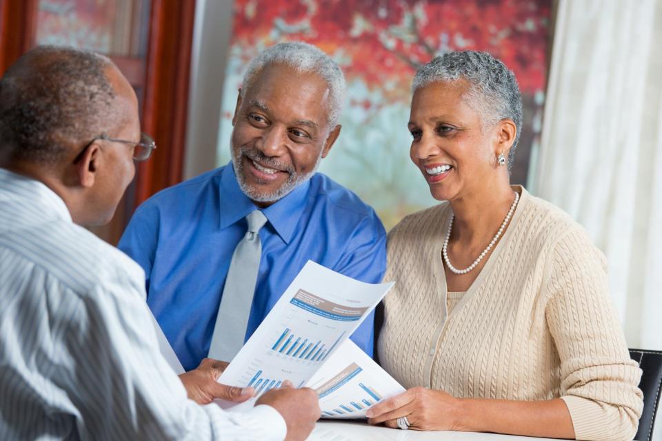 Two adults looking at financial paperwork with advisor.