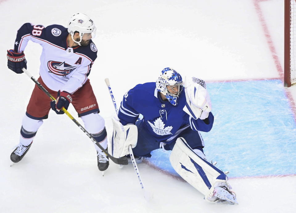 Toronto Maple Leafs goaltender Frederik Andersen (31) makes a glove save as Columbus Blue Jackets center Boone Jenner (38) looks on during the first period of an NHL Eastern Conference Stanley Cup playoff game in Toronto on Sunday, Aug. 9, 2020. (Nathan Denette/The Canadian Press via AP)
