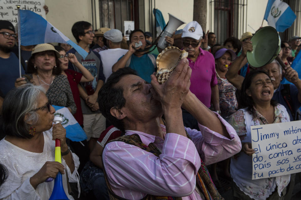 A man blows a sea shell as a trumpet during a protest against Guatemalan President Jimmy Morales organized by civil society groups in front of the Presidential House in Guatemala City, Saturday, July 27, 2019. (AP Photo/ Oliver de Ros)