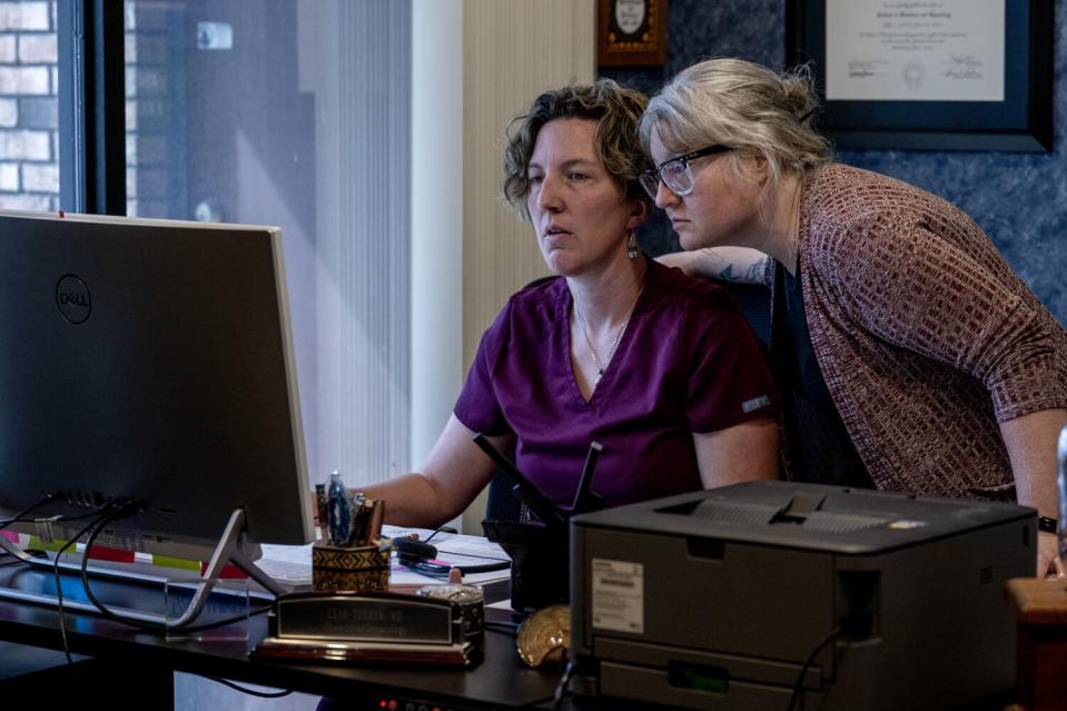 Two women look at a computer screen.