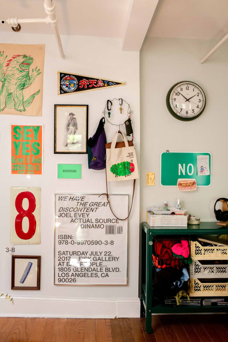 Decorative items are attached to a white wall next to a green cabinet with storage.