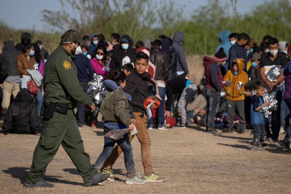 A U.S. Border Patrol Agent escorts two asylum-seeking unaccompanied minors from Central America as others take refuge near a baseball field after crossing the Rio Grande river into the United States from Mexico on rafts, in La Joya, Texas, on March 19<span class="copyright">Adrees Latif—Reuters</span>