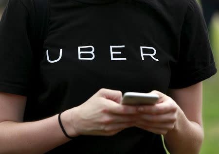 An Uber representative registers people on his smartphone during the kick off of a citywide jobs tour in the Queens borough of New York July 21, 2015. REUTERS/Shannon Stapleton