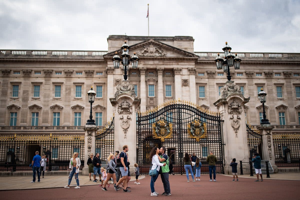 Tourists gather outside Buckingham Palace  (PA)