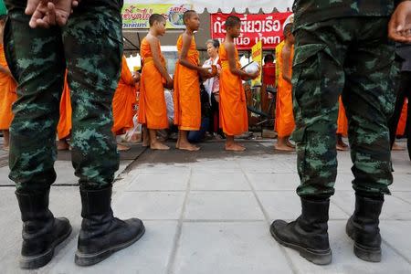 Buddhist monks receive food from people while soldiers watch on outside Dhammakaya temple in Pathum Thani province, Thailand February 23, 2017. REUTERS/Jorge Silva