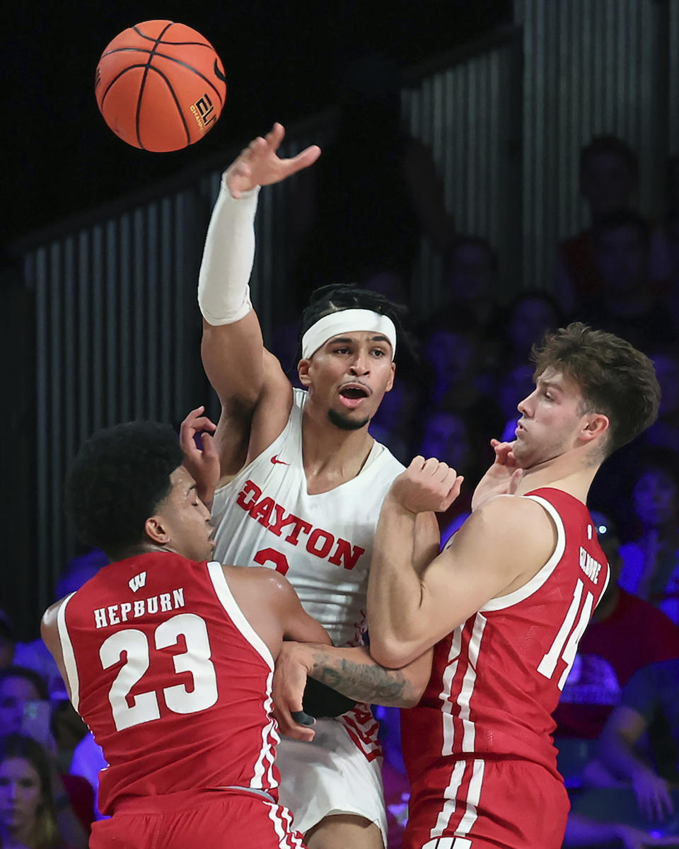 This photo provided by Bahamas Visual Services shows Dayton forward Toumani Camara passing while being double teamed by Wisconsin's Chucky Helburn (23) and Carter Gilmore (14) during an NCAA college basketball game at the Battle 4 Atlantis at Paradise Island, Bahamas, Wednesday, Nov. 23, 2022. . (Tim Aylen/Bahamas Visual Services via AP)