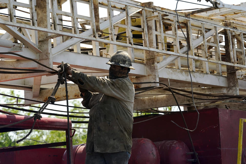 A well worker moves equipment at a site on Molly Rooke's ranch where an orphaned well was plugged, Tuesday, May 18, 2021, near Refugio, Texas. Oil and gas drilling began on the ranch in the 1920s and there were dozens of orphaned wells that needed to be plugged for safety and environmental protection. (AP Photo/Eric Gay)