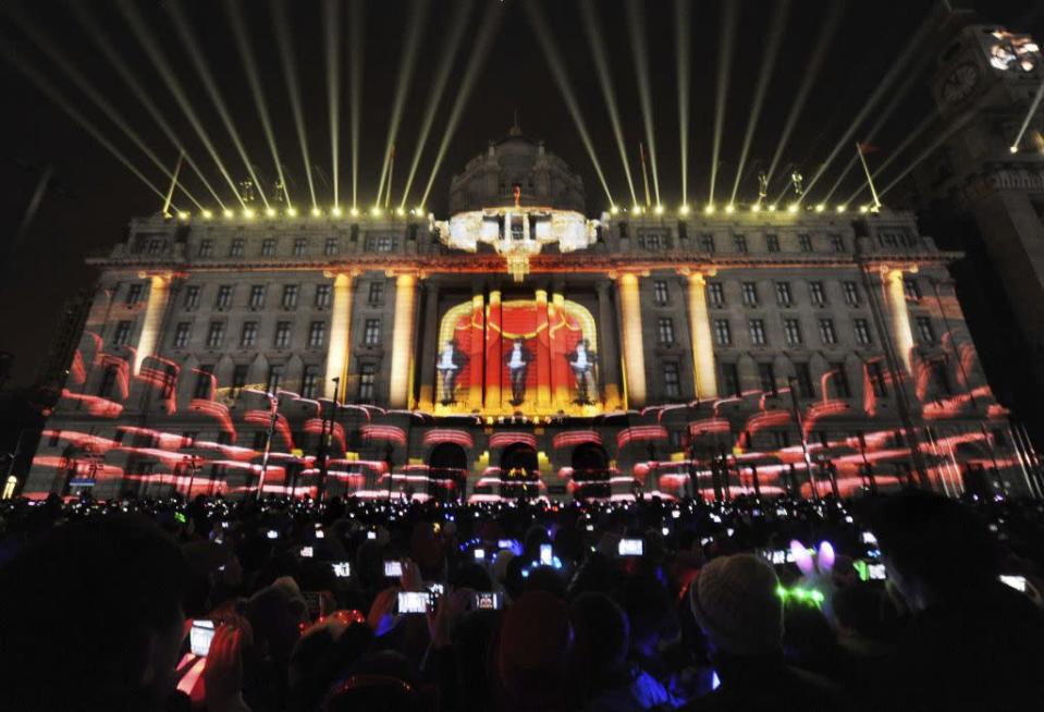 Visitors take pictures and videos during a light show as part of a New Year countdown celebration at the financial square on the Bund in Shanghai December 31, 2012. Picture taken December 31, 2012.