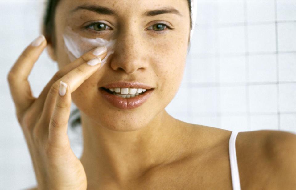 woman putting lotion on face