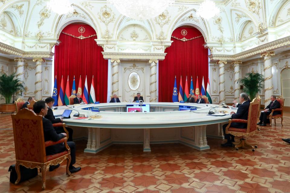 CSTO leaders sit around a large round table above a tiled floor and under a carved, gilded ceiling