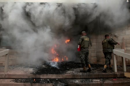 Soldiers extinguish burning tires after a demonstration against government privatisation plans in healthcare and education in Tegucigalpa