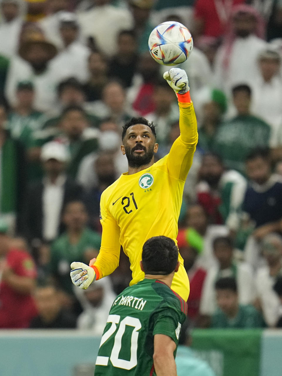 Saudi Arabia's goalkeeper Mohammed Al-Owais stops a shot above Mexico's Henry Martin during the World Cup group C soccer match between Saudi Arabia and Mexico, at the Lusail Stadium in Lusail, Qatar, Wednesday, Nov. 30, 2022. (AP Photo/Julio Cortez)