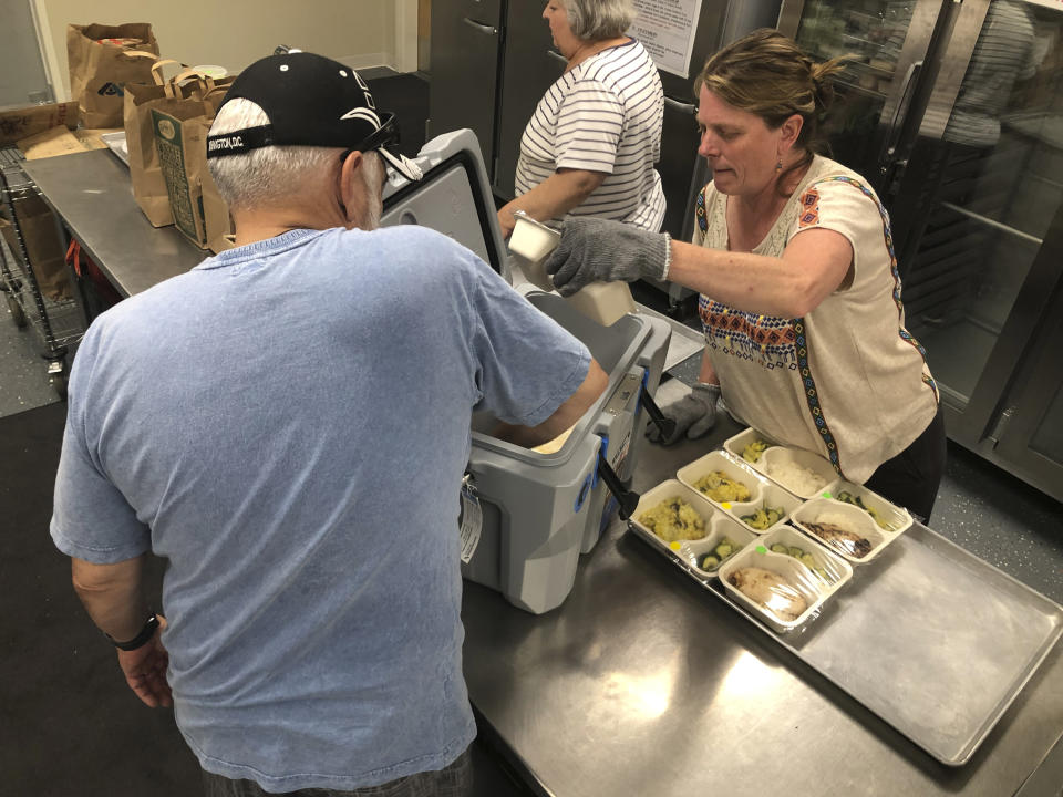 In this photo taken Friday, June 14, 2019, volunteers including Shelley Winship and retired accountant Ralph Nava, left, pick up food packages to deliver to homebound families and dependent children in Santa Fe, N.M., at the headquarters for Kitchen Angels. An annual report on childhood well-being from the Annie E. Casey Foundation ranks New Mexico last among 50 states that includes measures of poverty, health care, education and family support. The number of children living in poverty has swelled over the past three decades in fast-growing, ethnically diverse states such as Texas, Arizona and Nevada as the nation's population center shifts south and west. (AP Photo/Morgan Lee)