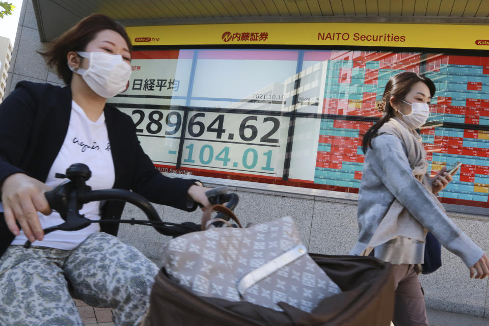 People pass by an electronic stock board of a securities firm in Tokyo, Monday, Oct. 18, 2021. Asian shares were mostly lower on Monday after China reported its economy grew at a meager 4.9% annual pace in July-September. (AP Photo/Koji Sasahara)