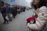 A woman holds a dog in front of people waiting for a bus to take them to Beijing from Yanjiao, Hebei province, China, November 13, 2015. REUTERS/Damir Sagolj