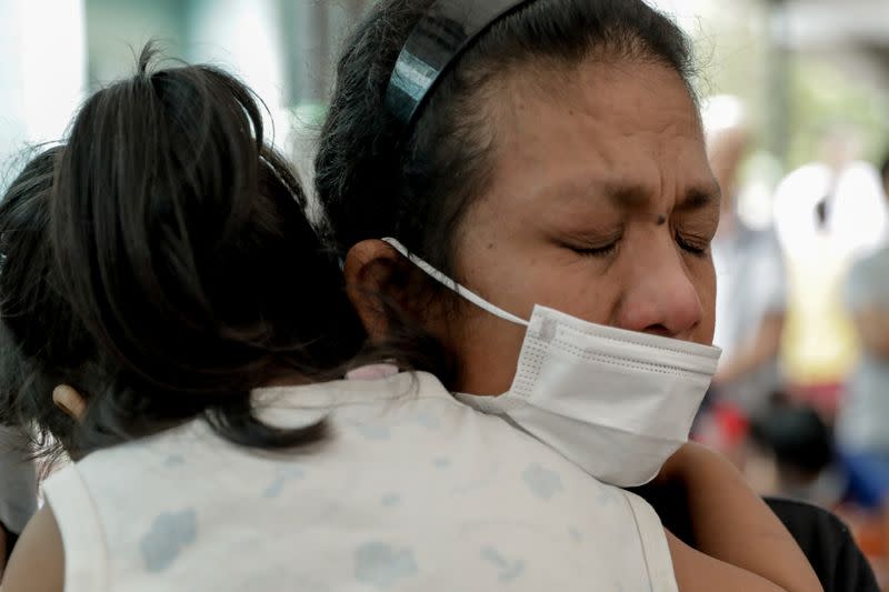 A woman displaced by the erupting Taal Volcano becomes emotional while attending a Catholic mass in an evacuation center,