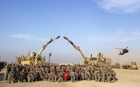 Soldiers from the 3rd Brigade Combat Team, 1st Cavalry Division hold their unit's flag for a photograph while waiting at a staging area in Camp Adder to be part of the last U.S. military convoy to leave the country near Nasiriyah, Iraq on December 17, 2011. REUTERS/Lucas Jackson/Pool