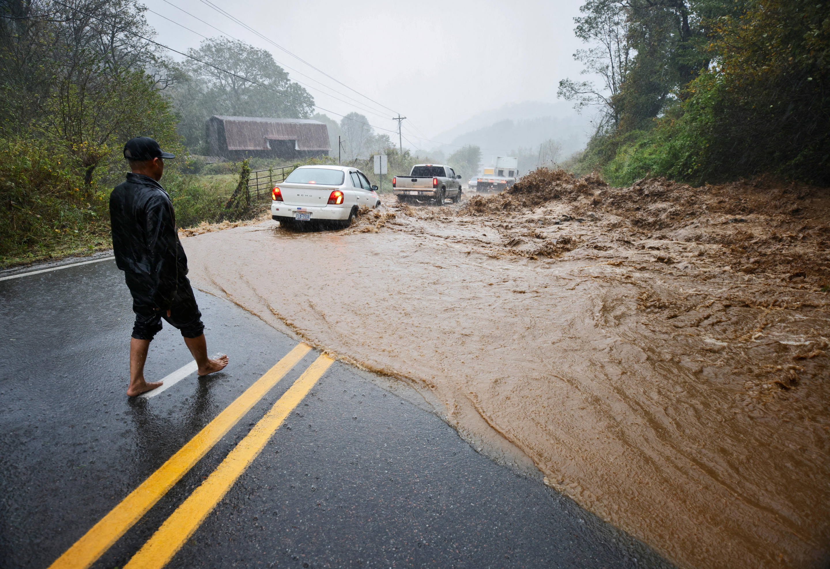 Un residente local observa cómo los coches atraviesan un traicionero tramo de carretera inundada después de que él ayudara a sacar rocas del agua mientras la tormenta tropical Helene golpea, en las afueras de Boone, Carolina del Norte, EE.UU. 27 de septiembre de 2024.  REUTERS/Jonathan Drake