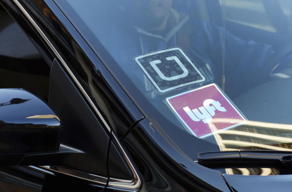 FILE - In this Jan. 12, 2016, file photo, a ride-share car displays Lyft and Uber stickers on its front windshield in downtown Los Angeles. The California Supreme Court has rejected a challenge to the ballot measure that kept app-based ride-hailing and delivery drivers independent contractors instead of employees eligible for benefits and job protections. The court on Wednesday, Feb. 3, 2021, declined to hear the case brought by drivers and unions who had opposed the measure. (AP Photo/Richard Vogel, File)