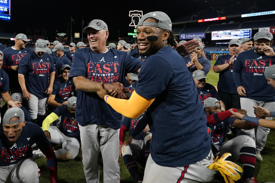 Atlanta Braves' Brian Snitker, left, and Ronald Acuna Jr. celebrate after clinching their sixth consecutive NL East title by defeating the Philadelphia Phillies in a baseball game, Wednesday, Sept. 13, 2023, in Philadelphia. (AP Photo/Matt Slocum)