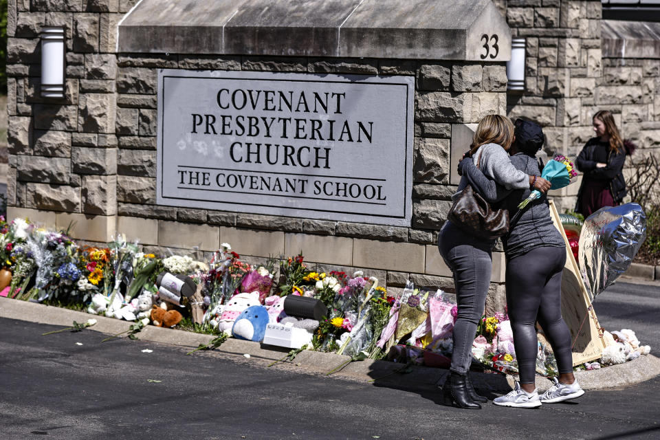 Two women hug at a memorial at the entrance to The Covenant School on Wednesday, March 29, 2023, in Nashville, Tenn. (AP Photo/Wade Payne)