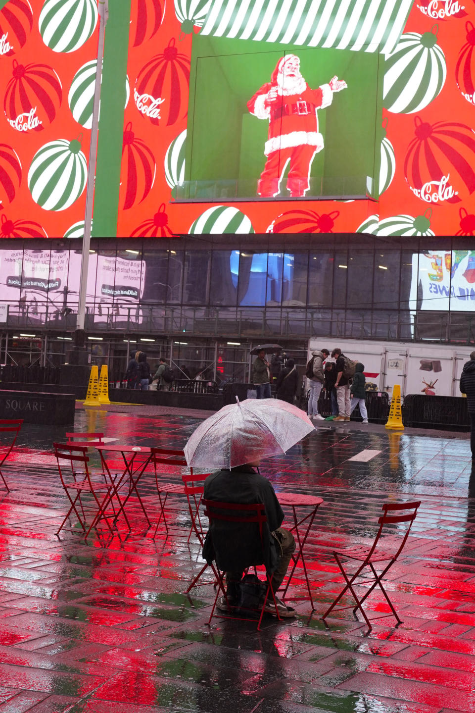 A man sits under an umbrella in a wet Times Square in New York, Monday, Dec. 18, 2023. A storm moving up the East Coast brought heavy rain and high winds to the Northeast on Monday, threatening flooding, knocking out power to hundreds of thousands, and forcing flight cancelations and school closings. (AP Photo/Seth Wenig)