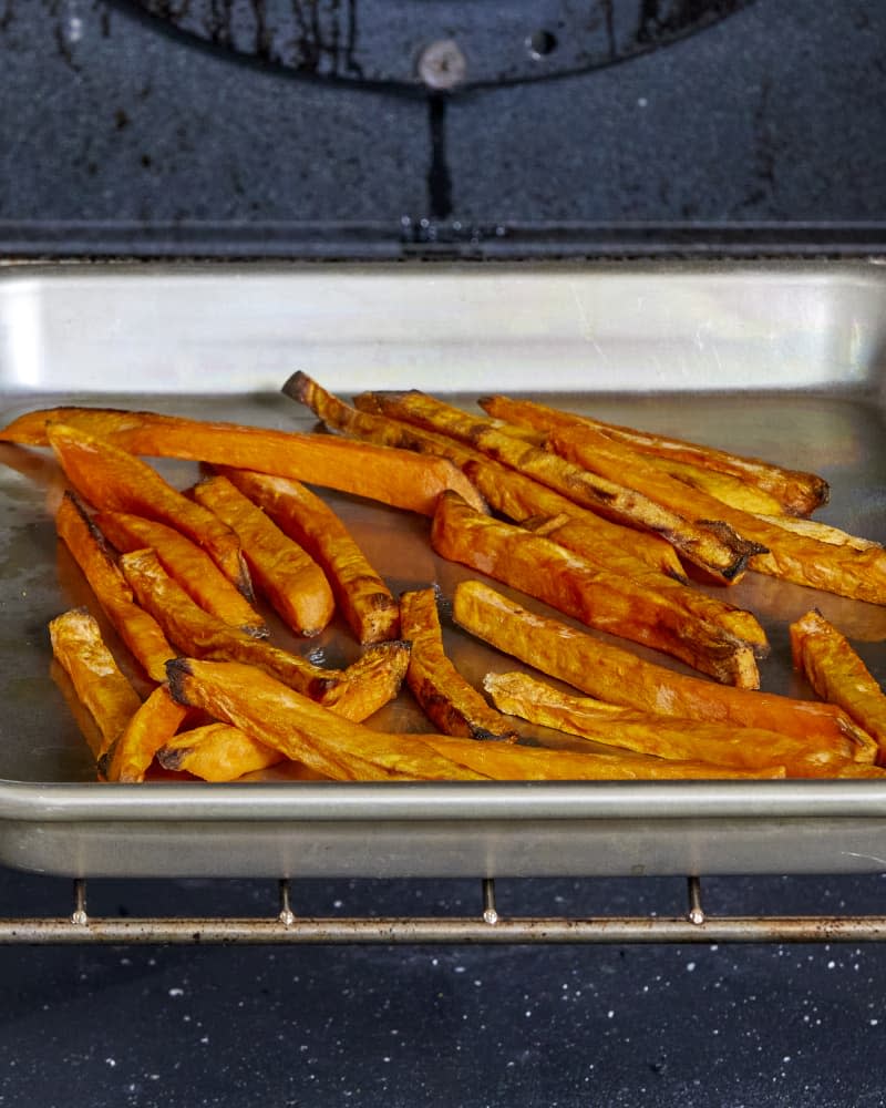 Head on view of sweet potato fries baking inside an oven.