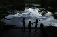 Children play at the edge of a lagoon at the Ecological Reserve of Guapiacu (REGUA) in Rio de Janeiro April 19, 2014. Picture taken April 19, 2014. REUTERS/Pilar Olivares (BRAZIL - Tags: ENVIRONMENT)