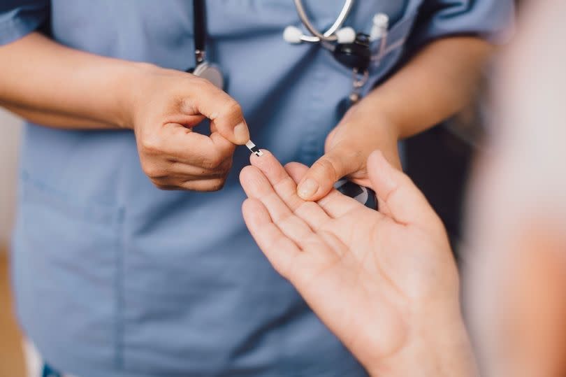 Nurse measures the blood sugar level of a patient