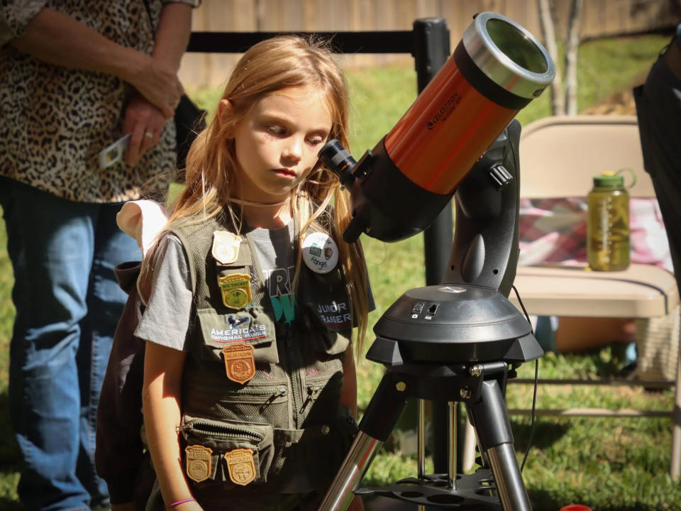 File: A junior ranger looks through a solar-filtered telescope searching for sunspots.