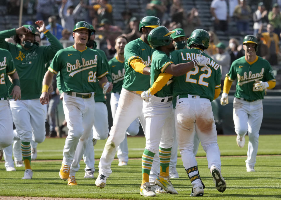 Oakland Athletics' Ramon Laureano (22) celebrates with teammates after two runs scored on a throwing error by Minnesota Twins third baseman Luis Arraez during the 10th inning of a baseball game Wednesday, April 21, 2021, in Oakland, Calif. Laureano safe at first. Oakland won 13-12. (AP Photo/Tony Avelar)