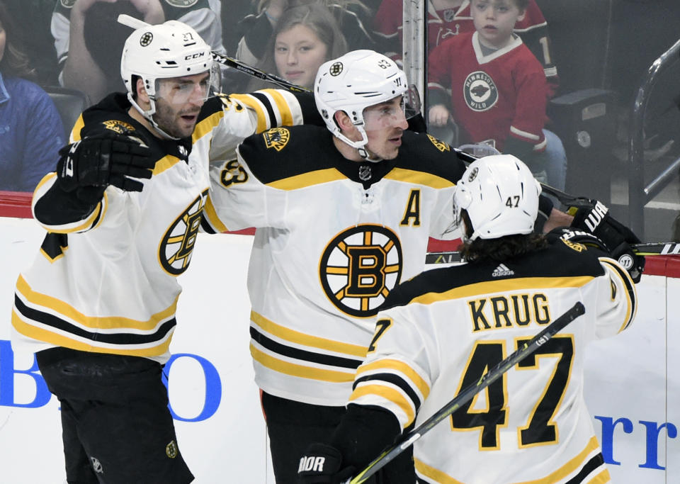 Boston Bruins’ Patrice Bergeron (37), Brad Marchand (63) and Torey Krug (47) celebrate a goal by Marchand against the Minnesota Wild during the overtime period of an NHL hockey game Sunday, March 25, 2018, in St. Paul, Minn. The Bruins won 2-1 in overtime. (AP Photo/Hannah Foslien)