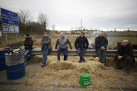 Farmers sit by a barricade as farmers block a highway Tuesday, Jan. 30, 2024 in Jossigny, east of Paris. With protesting farmers camped out at barricades around Paris, France's government hoped to calm their anger with more concessions Tuesday to their complaints that growing and rearing food has become too difficult and not sufficiently lucrative. (AP Photo/Christophe Ena)