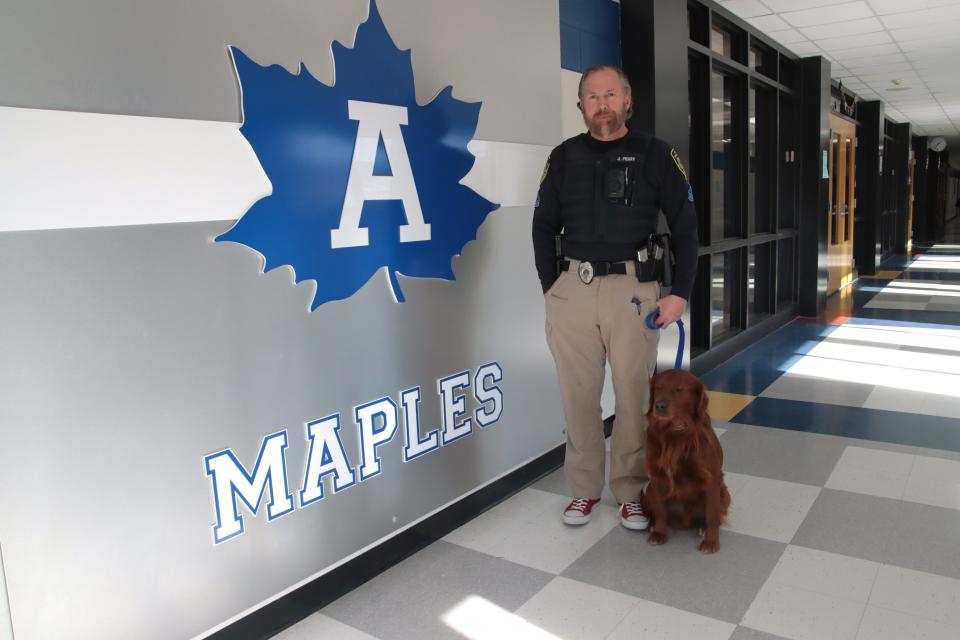 Adrian School Resource Officer Joshua Perry, is pictured with Charlie, the Adrian school district's police and therapy dog, Wednesday, Feb. 7, 2024, at Adrian High School.